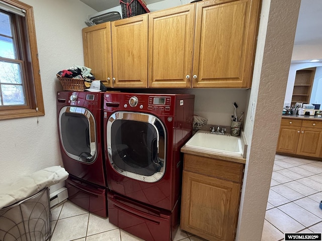 laundry room with light tile patterned floors, a sink, washing machine and dryer, and cabinet space