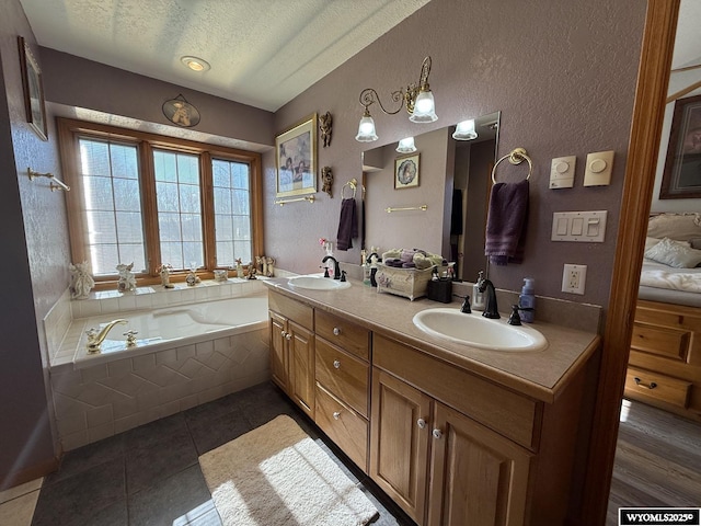 full bathroom with a garden tub, a sink, a textured ceiling, and double vanity