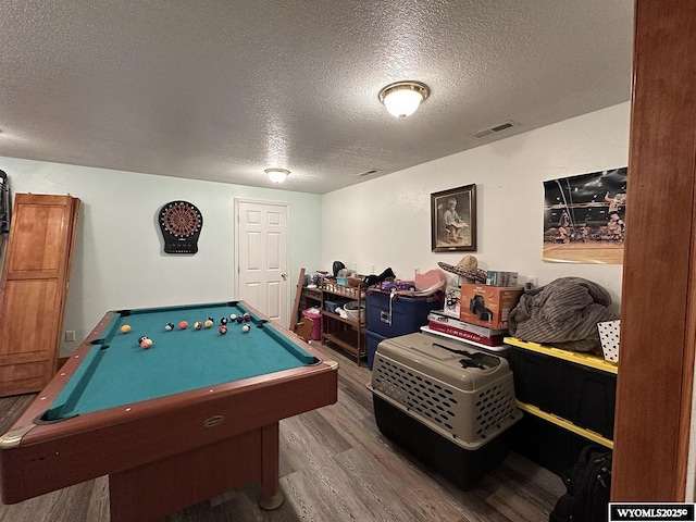 rec room with a textured ceiling, billiards, wood finished floors, and visible vents