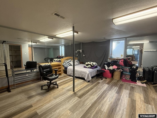 bedroom featuring a textured ceiling, wood finished floors, and visible vents