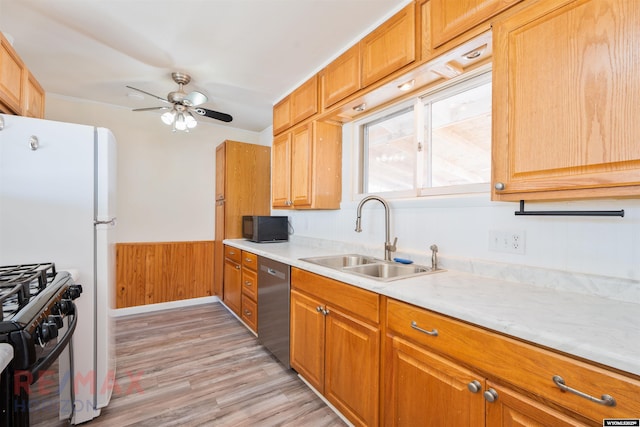 kitchen featuring light wood finished floors, light countertops, a sink, ceiling fan, and black appliances