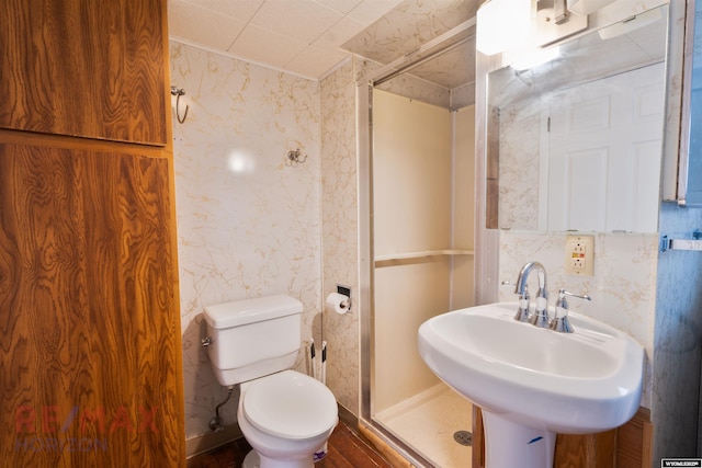 full bathroom featuring toilet, wallpapered walls, a sink, and a stall shower