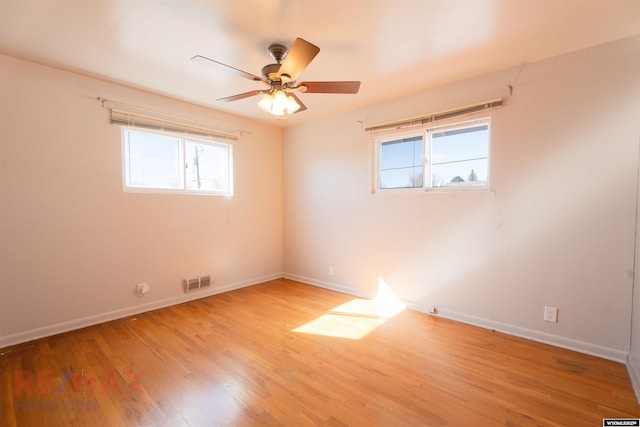 empty room with light wood-type flooring, visible vents, ceiling fan, and baseboards