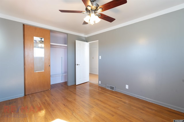 unfurnished bedroom with crown molding, visible vents, light wood-style flooring, ceiling fan, and baseboards