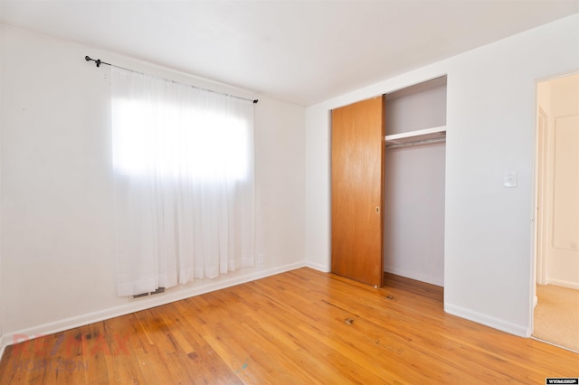 unfurnished bedroom featuring a closet, light wood-style flooring, and baseboards