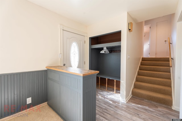 entrance foyer featuring light wood-type flooring, stairway, and wainscoting