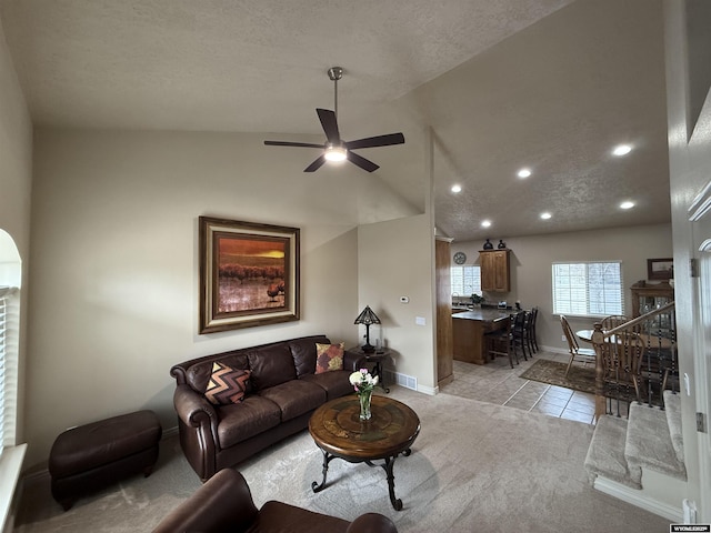 living room with baseboards, a ceiling fan, lofted ceiling, a textured ceiling, and light tile patterned flooring