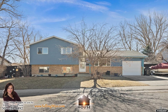 tri-level home with concrete driveway, brick siding, a front lawn, and an attached garage