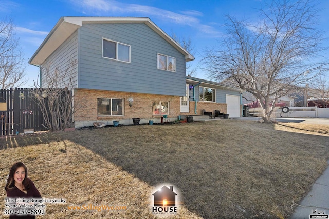 split level home featuring fence, a front lawn, and brick siding