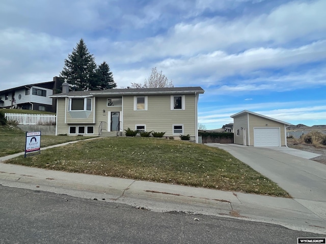 bi-level home featuring a front yard, driveway, an outdoor structure, and fence