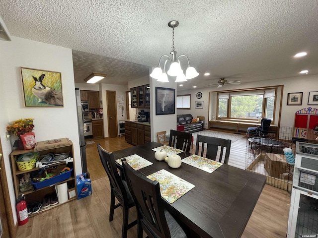 dining space with a textured ceiling, light wood-style flooring, and a notable chandelier