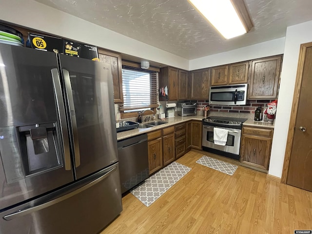 kitchen featuring stainless steel appliances, light wood-type flooring, a sink, and light countertops