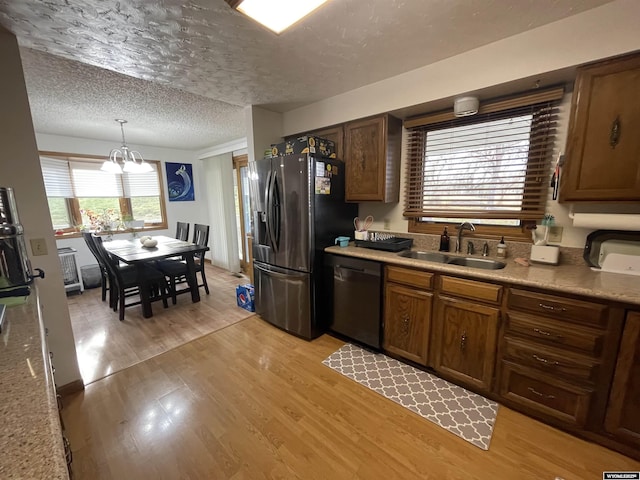 kitchen featuring light wood finished floors, black fridge with ice dispenser, a sink, a textured ceiling, and dishwasher