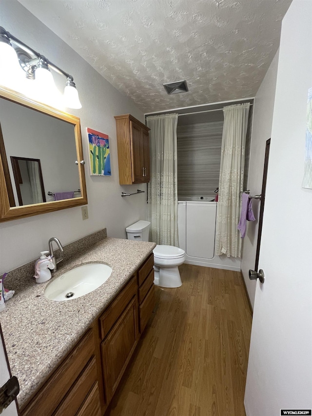 bathroom with shower / tub combo, toilet, wood finished floors, a textured ceiling, and vanity