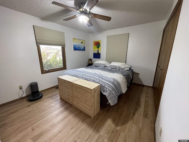 bedroom featuring a textured ceiling, ceiling fan, and light wood-style flooring