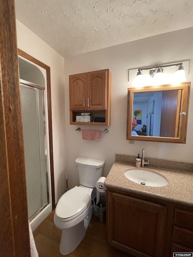 full bath featuring toilet, a shower stall, vanity, and a textured ceiling