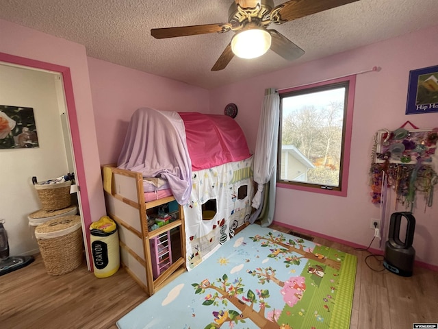 bedroom featuring a textured ceiling, wood finished floors, visible vents, a ceiling fan, and baseboards