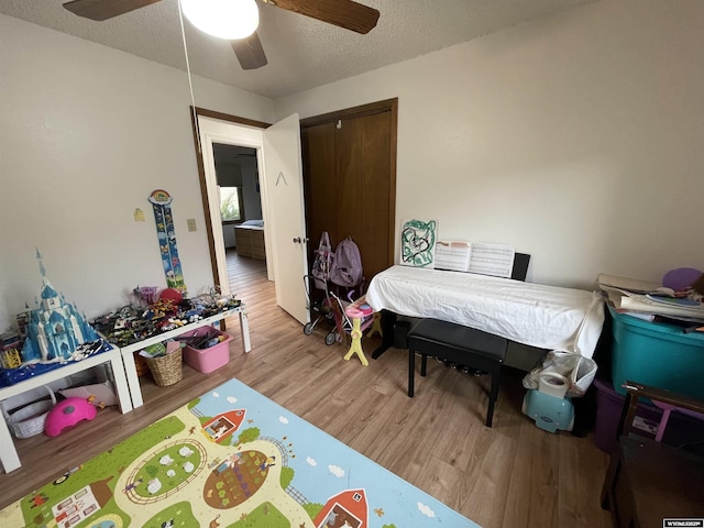 bedroom featuring a ceiling fan, a closet, a textured ceiling, and wood finished floors