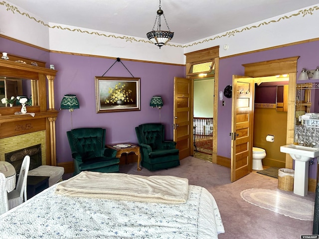 carpeted bedroom with a fireplace with raised hearth, a sink, and connected bathroom