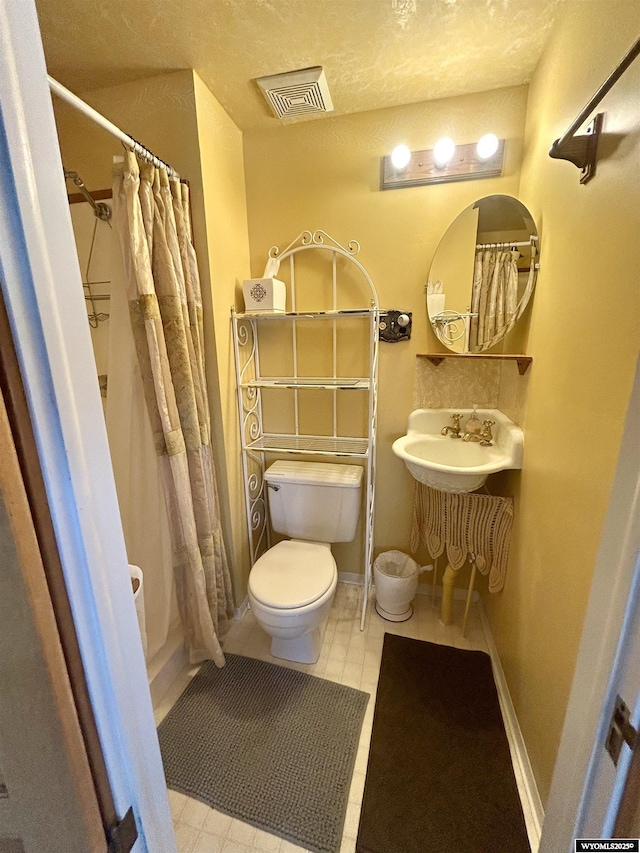 bathroom featuring toilet, curtained shower, baseboards, and visible vents