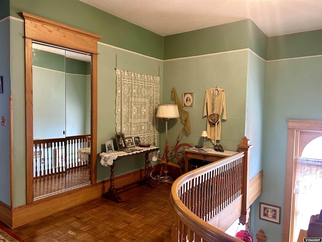 hall featuring a textured ceiling and baseboards