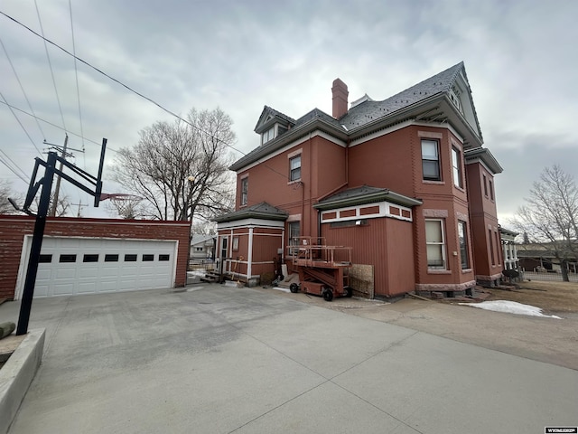 view of side of property with a garage, a chimney, and an outbuilding