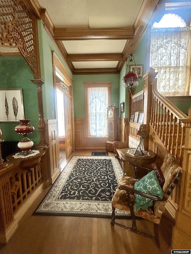 doorway with a wainscoted wall, beamed ceiling, wood finished floors, stairs, and crown molding