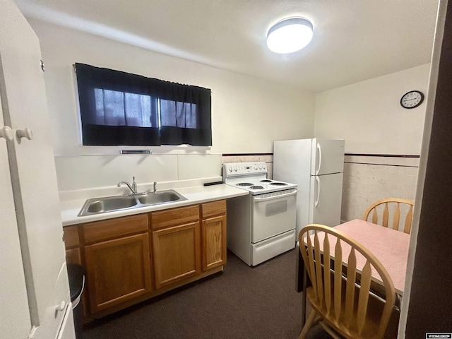 kitchen featuring brown cabinets, light countertops, wainscoting, a sink, and white appliances