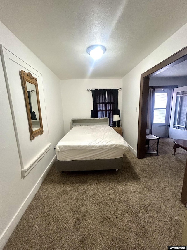 carpeted bedroom featuring baseboards and a textured ceiling