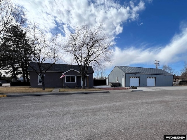 view of front of house with a garage, metal roof, and an outdoor structure