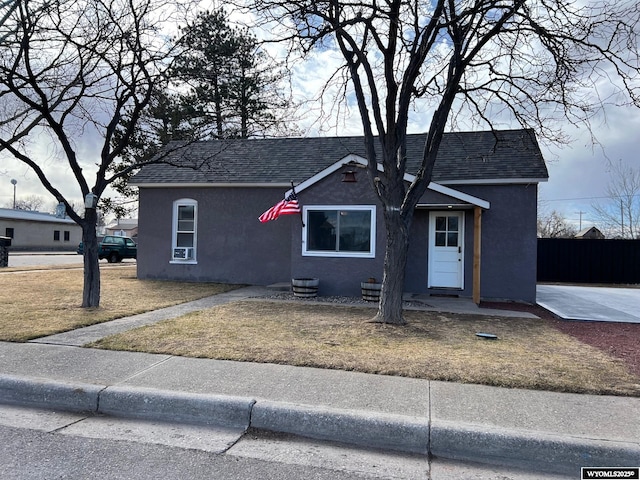 view of front of house with a front lawn, roof with shingles, and stucco siding