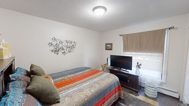 bedroom featuring a textured ceiling, baseboard heating, and dark wood finished floors