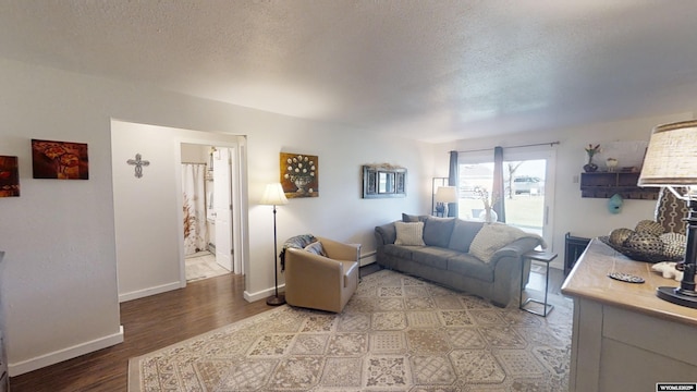 living room featuring baseboards, a textured ceiling, and light wood finished floors