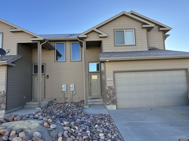 view of front of property featuring a shingled roof, concrete driveway, and an attached garage