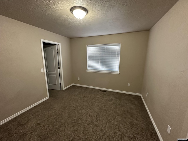 empty room featuring baseboards, visible vents, dark colored carpet, and a textured ceiling