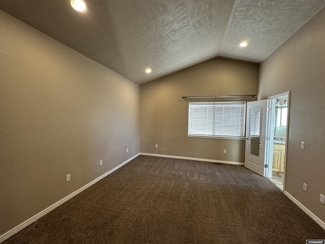 unfurnished room featuring lofted ceiling, baseboards, a textured ceiling, and dark colored carpet