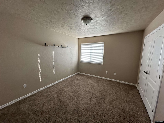 empty room featuring a textured ceiling, baseboards, and carpet flooring