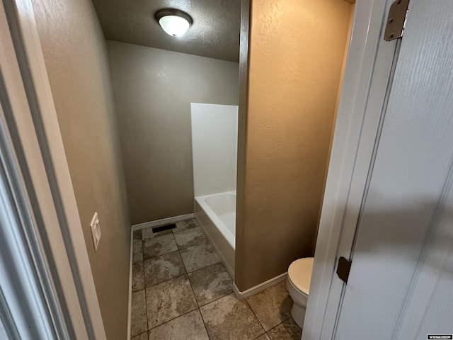 full bath featuring baseboards, tile patterned floors, toilet, and a tub