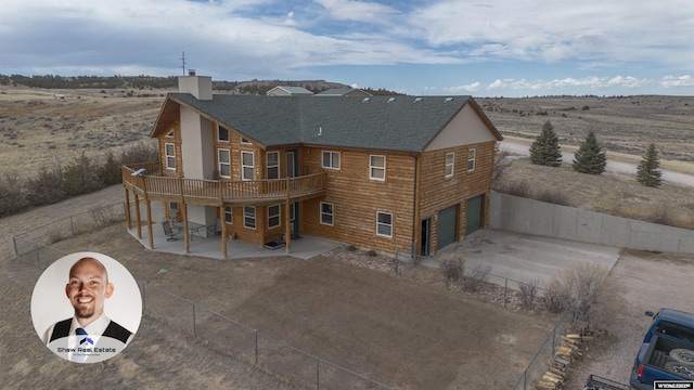 rear view of house featuring driveway, a chimney, an attached garage, fence, and a patio area