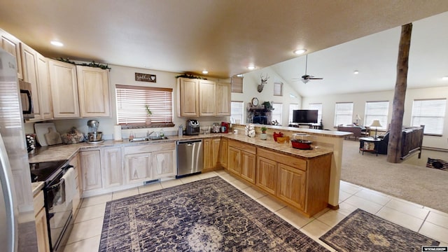 kitchen with light tile patterned floors, appliances with stainless steel finishes, a healthy amount of sunlight, a sink, and a peninsula