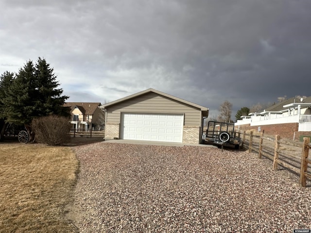 exterior space with a garage, brick siding, fence, and an outdoor structure