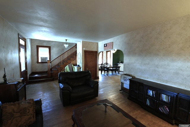 living area featuring arched walkways, cooling unit, stairway, and wood finished floors