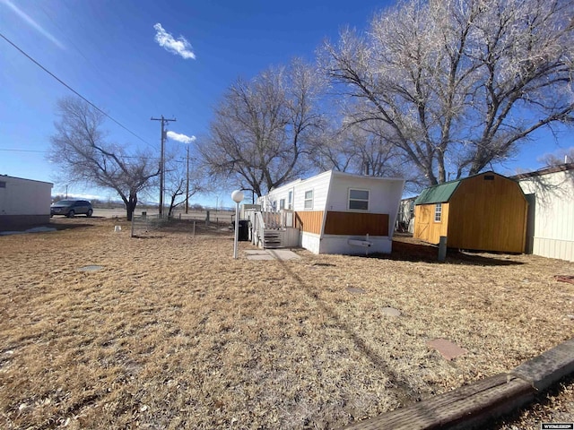 view of yard featuring an outbuilding, a shed, and fence