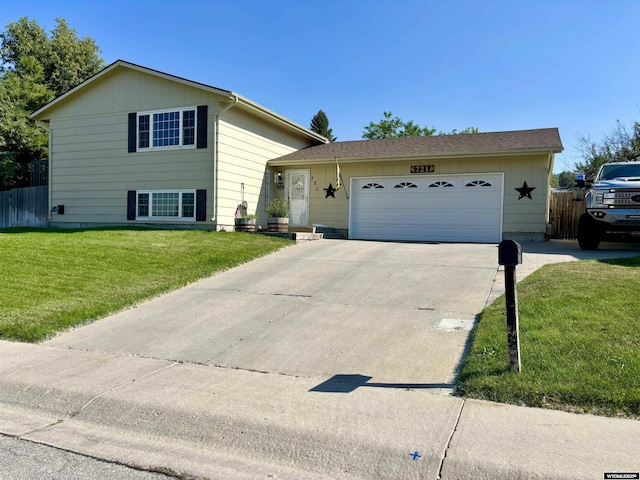 view of front of property featuring a garage, driveway, fence, and a front yard