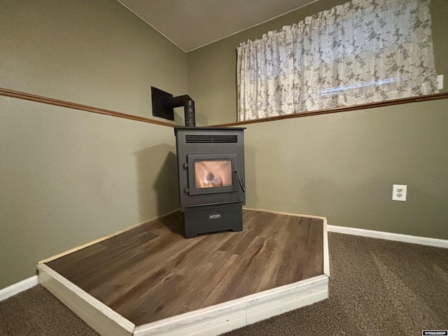 interior details featuring carpet flooring, a wood stove, and baseboards