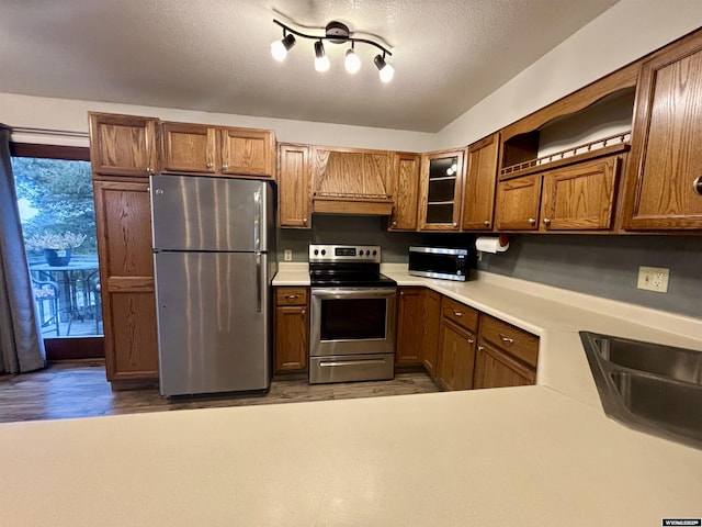 kitchen with a sink, light countertops, appliances with stainless steel finishes, open shelves, and custom range hood