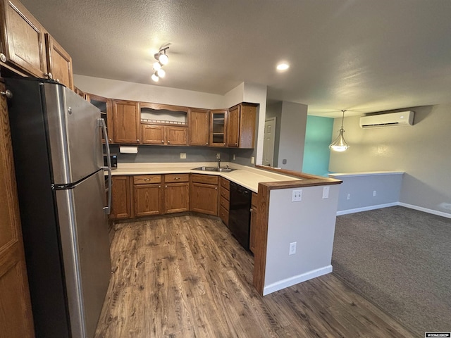 kitchen with a sink, an AC wall unit, freestanding refrigerator, brown cabinets, and dishwasher