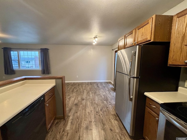 kitchen featuring range with electric stovetop, baseboards, black dishwasher, light wood-type flooring, and brown cabinetry