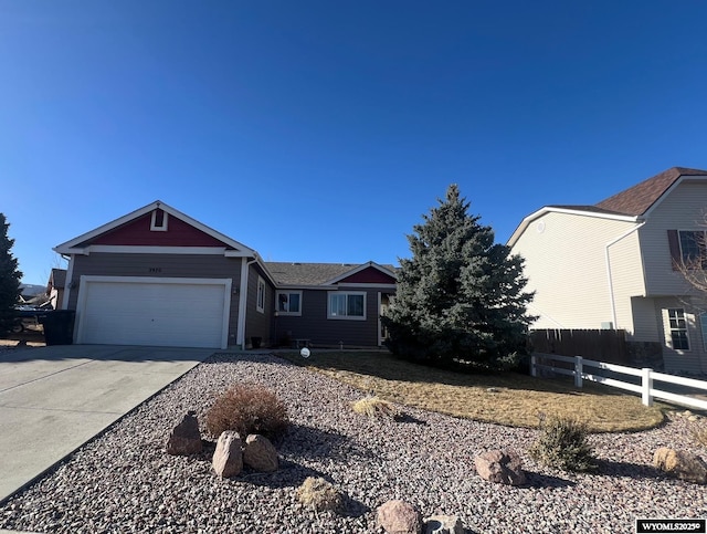 view of front of property featuring driveway, an attached garage, and fence