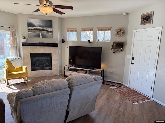 living area with a fireplace, plenty of natural light, wood finished floors, and baseboards